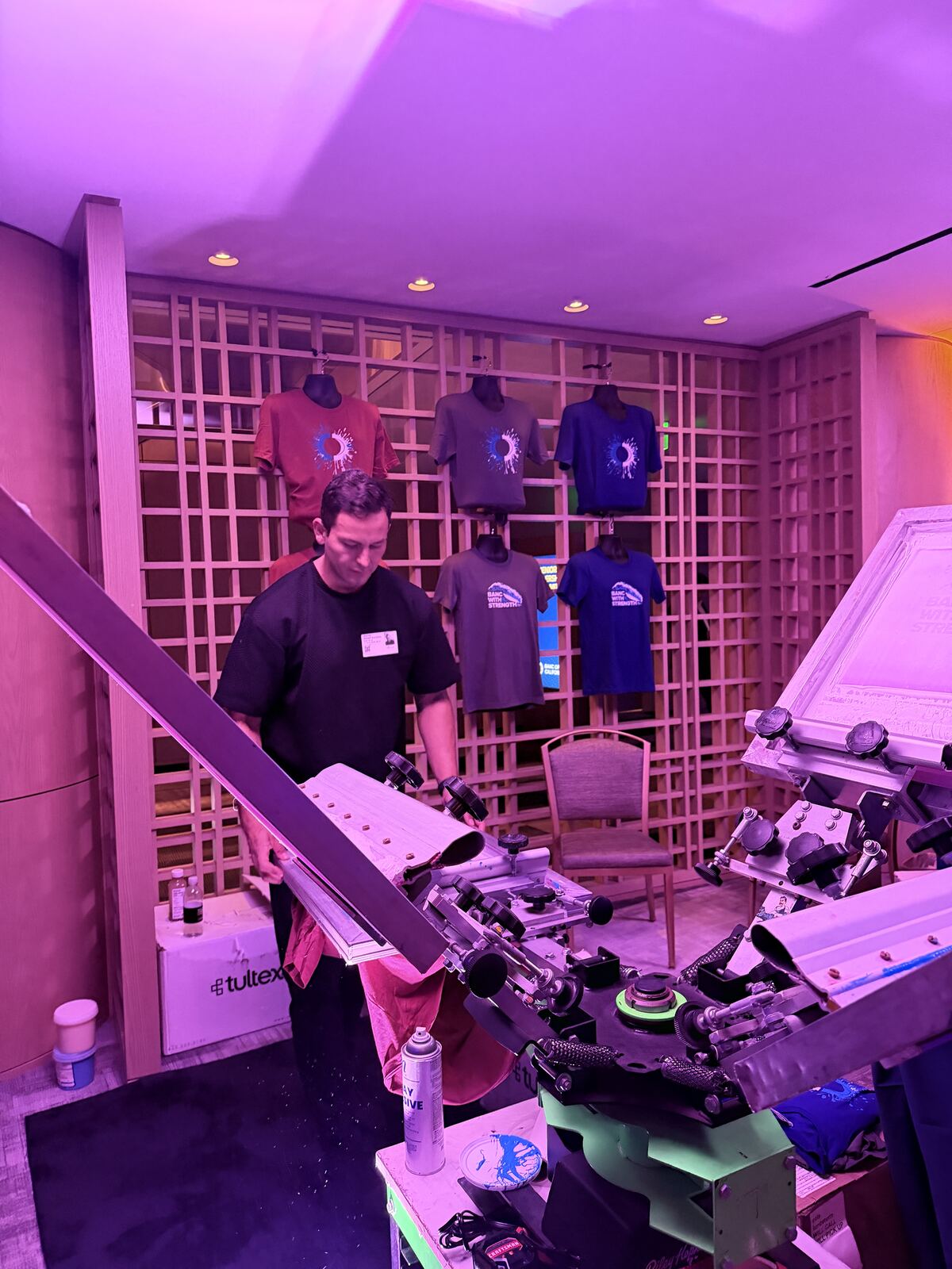 Staff member at an indoor trade show booth presenting decorated merchandise to event attendees